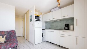 A compact kitchen with white cabinets, a microwave, a washing machine, and a coffee maker. - Valras Apartment with Sea View (Valras-Plage)