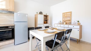 A modern kitchen with a built-in oven, a refrigerator, and a dining area with a table set for four.