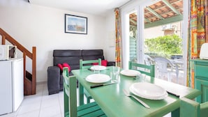 Comedor con una mesa lista para cuatro, un sofá y una ventana con vistas a zonas verdes.