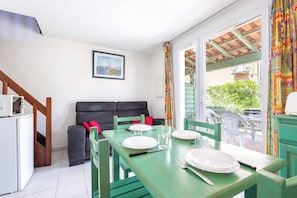 A dining area with a table set for four, a sofa, and a window with a view of greenery.
