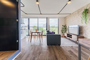 Ein modernes Wohnzimmer mit Sofa, Fernseher und Essbereich.