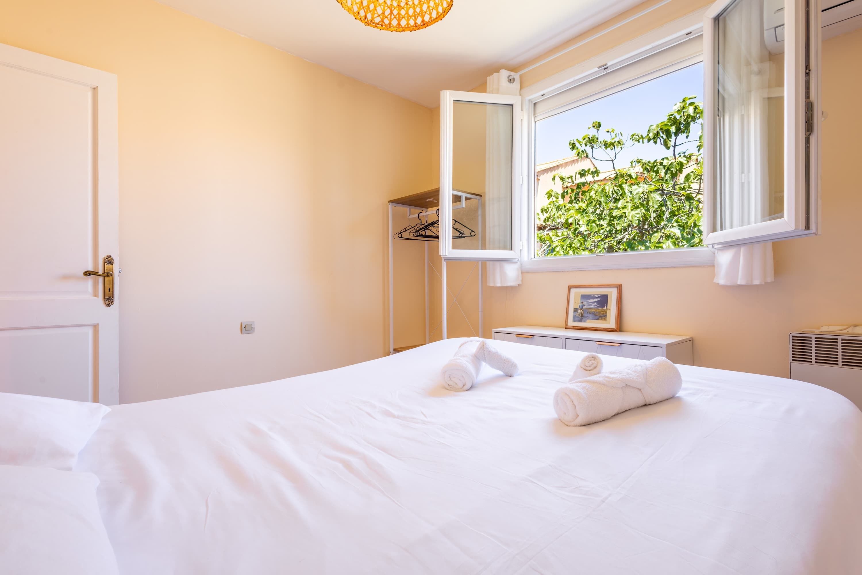 Una habitación de hotel con cama, ventana con vistas, armario y espejo.