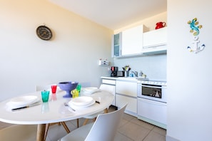 Une cuisine moderne avec des meubles blancs, une table à manger avec de l’assiette et des couverts, et un four à micro-ondes.