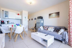 Una sala de estar moderna con sofá, mesa de centro y zona de comedor con sillas y una mesa.