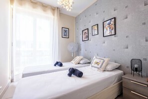 Una habitación de hotel con dos camas, un ventilador, una mesita de noche y una silla.