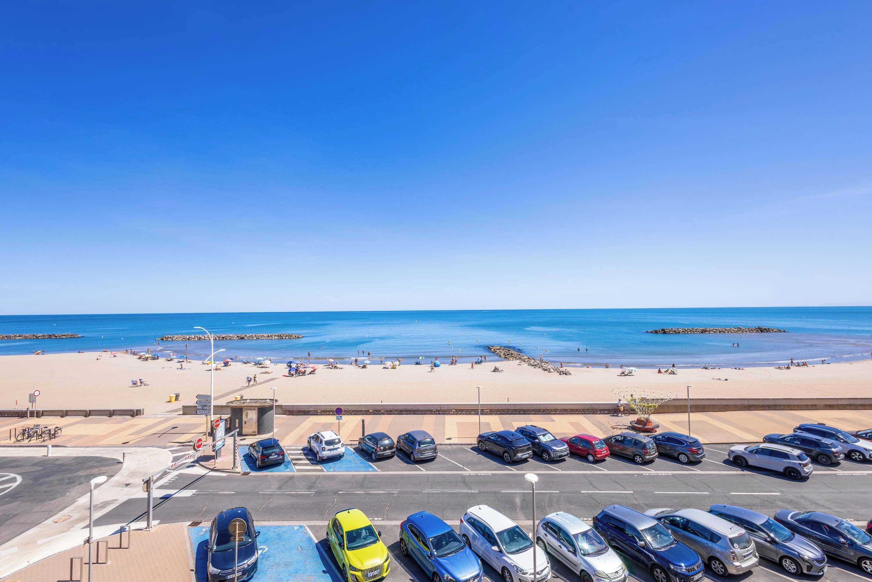 Ein Parkplatz mit Autos und einem Strand im Hintergrund.