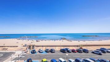 Ein Parkplatz mit Autos und einem Strand im Hintergrund.