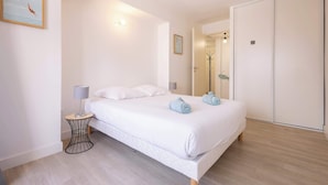 Une chambre à coucher comprenant un lit, des lampes de chevet, une table de chevet, un miroir et une armoire.