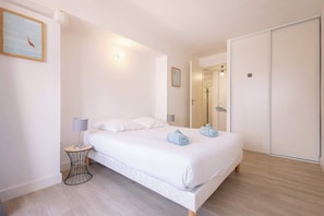 A bedroom with a bed, bedside lamps, a bedside table, a mirror, and a wardrobe.