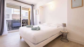 Une chambre d’hôtel avec un lit, une table de chevet, une lampe, un tableau encadré et une vue sur l’extérieur, accessible par une porte coulissante.