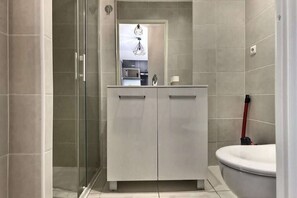 Une salle de bain moderne avec une douche à parois de verre, un meuble-lavabo blanc doté de deux tiroirs et une baignoire blanche.