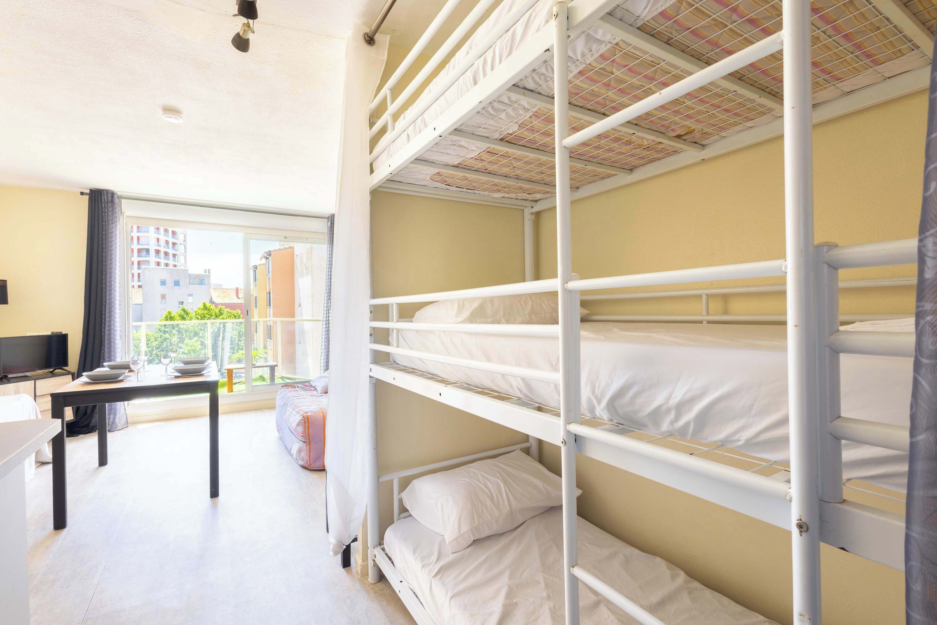 Une chambre avec un lit superposé, un bureau et une télévision.