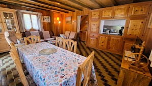 Een gezellig interieur van een chalet, met een eethoek, houten kastjes en een keuken.