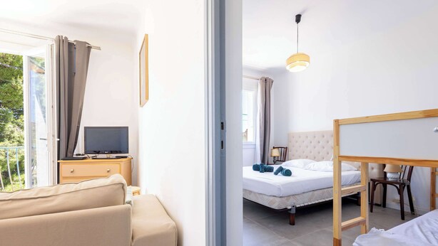 A room with a bed, a desk with a computer, a chair, and a window with curtains.