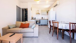 A living room with a sofa, a table, and a dining area with chairs and a table.