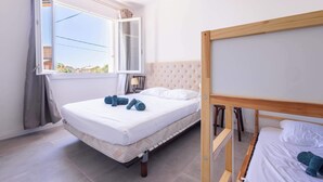 A bedroom with a bed, a window, a bedside table, and a lamp.