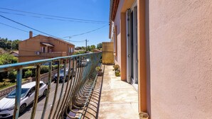 A balcony with a metal railing overlooking a street with parked cars.