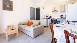 A modern living room with a sofa, a small wooden table, and a dining area with a table set for two.