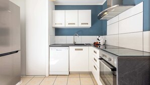 A modern kitchen with white cabinets, a dishwasher, a stove, and a sink.