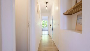 A narrow hallway with wooden flooring, white walls, and a ceiling light fixture.