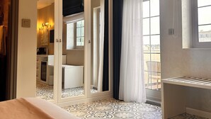 A hotel room with a bed, a wardrobe, a bathroom with a mirror, and a balcony with a view. - Palazzo De La Sengle Boutique Hotel (Senglea)