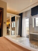 A hotel room with a bed, a wardrobe, a bathroom with a mirror, and a balcony with a view.
