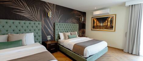 A hotel room with two beds, a large wall mural, an air conditioning unit, and a framed picture on the wall.