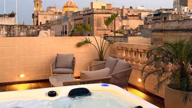 A rooftop terrace with a hot tub, seating area, and a cityscape view. - Palazzo De La Sengle Boutique Hotel (Senglea)
