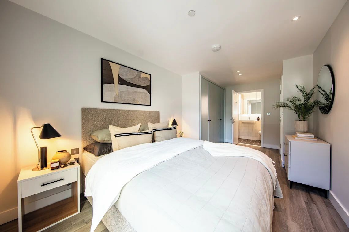 Une chambre à coucher moderne avec un grand lit, des tables de chevet, une commode, un miroir et un tableau au mur.