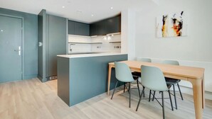 Une cuisine moderne dotée d’un îlot central, d’un coin repas avec une table et des chaises en bois, et d’un mur d’accent bleu.