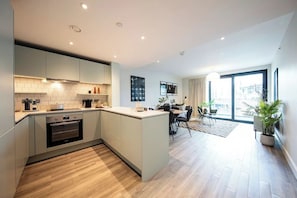 A modern kitchen with an island, built-in oven, and ample counter space. - Alameda - Campus Accommodation (Wembley)