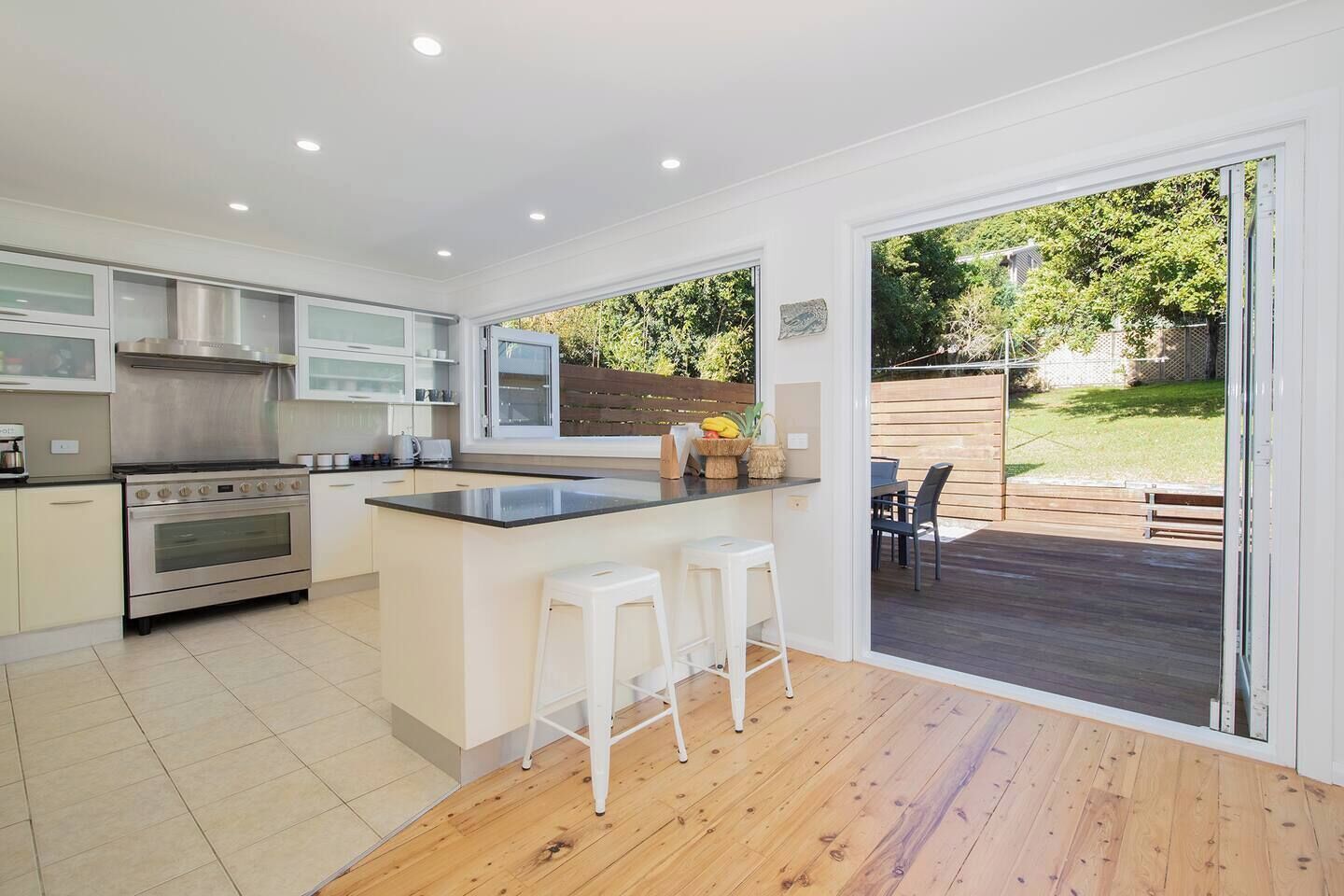 Prepare meals with ease in the spacious kitchen, where bi-fold windows open to the deck, making it simple to pass out drinks or chat with friends at the table outside.