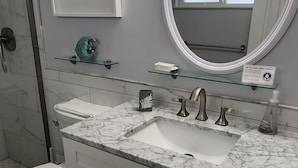 A bathroom with a white vanity, a sink, a mirror, and a toilet.