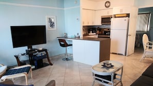 A compact living space with a TV, a small dining area, and a kitchenette.