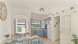 A dining area with a table and chairs, a kitchen with blue cabinets, and a white door. - Vacation 'Los Mangueros Beach 6 - Mogán' with Mountain View, Wi-Fi and Air Conditioning (Puerto de Mogán)