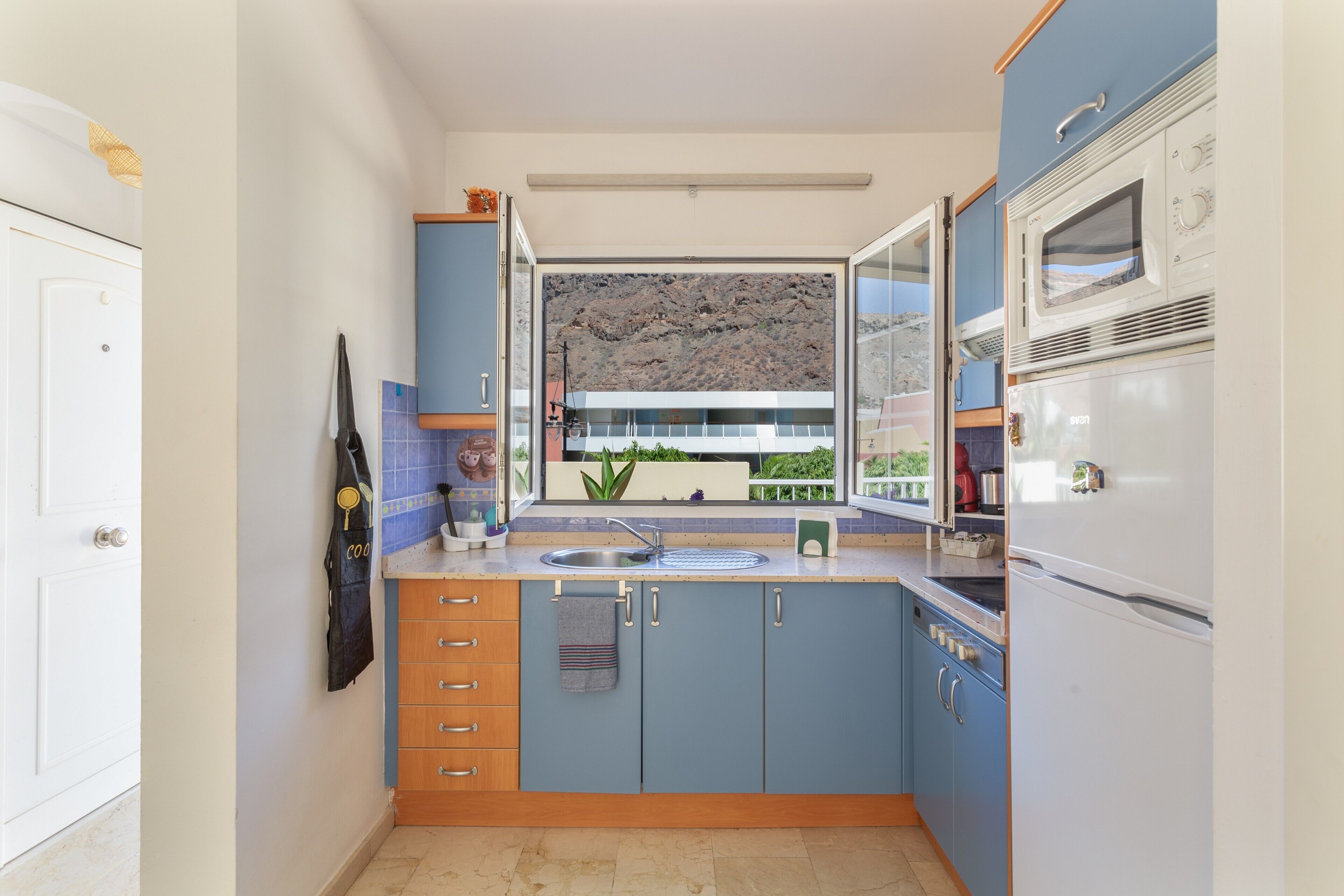 Une cuisine compacte avec fenêtre, un four à micro-ondes et un réfrigérateur.