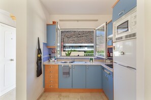Une cuisine compacte avec fenêtre, un four à micro-ondes et un réfrigérateur.