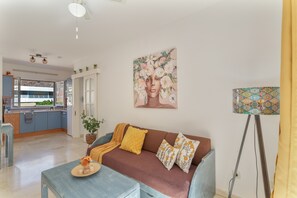 Un salon avec un canapé, une table basse, un tableau et une lampe.