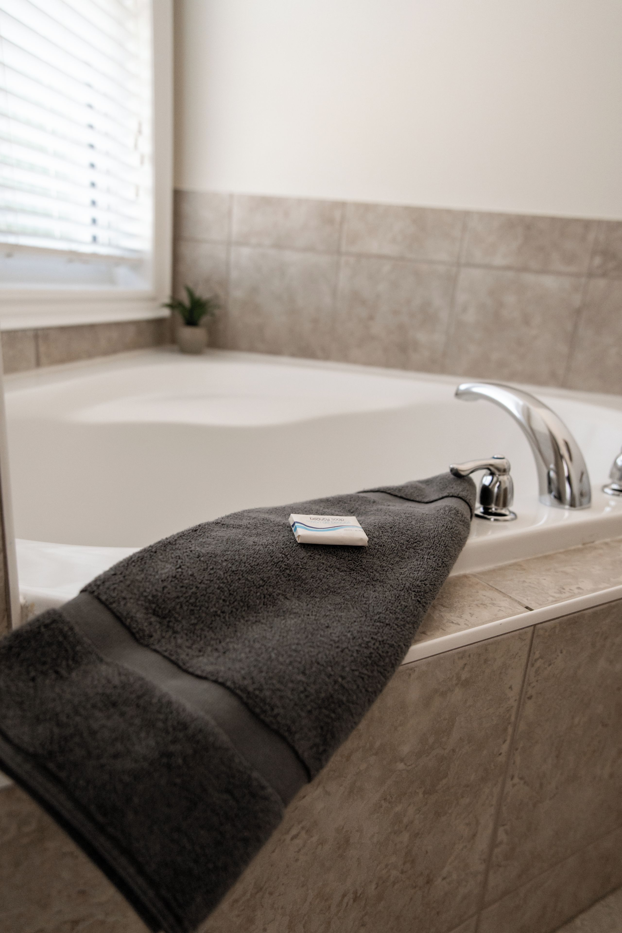 A bathroom with a bathtub, a towel, and a small potted plant.