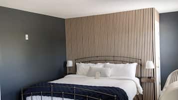 A bedroom with a bed, bedside tables, a wall-mounted light fixture, and a striped wall panel.