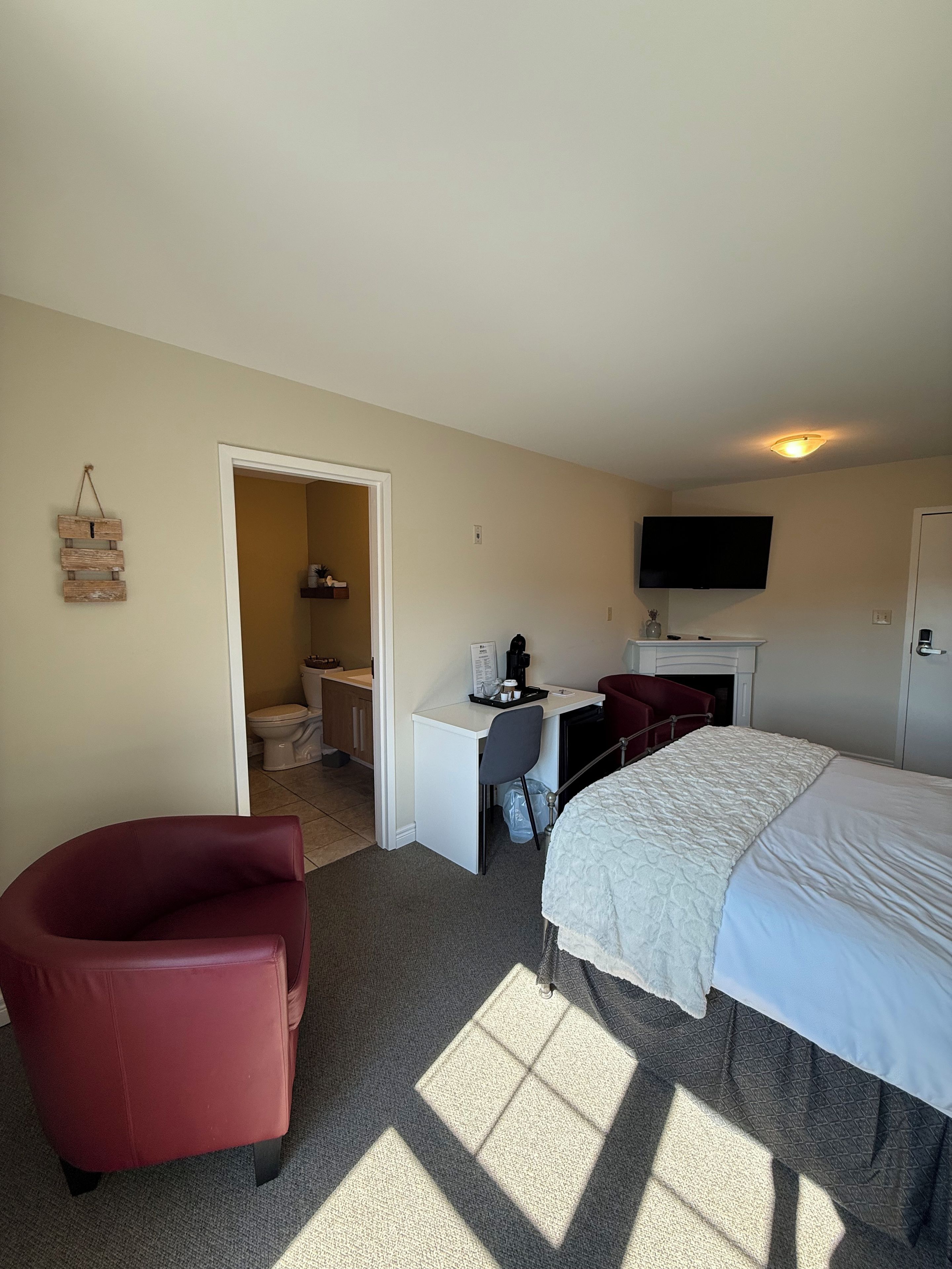 Una habitación de hotel con una cama, un escritorio con una silla, un televisor y una silla roja.