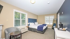 A hotel room with a bed, a desk, a chair, and a large window with blinds.