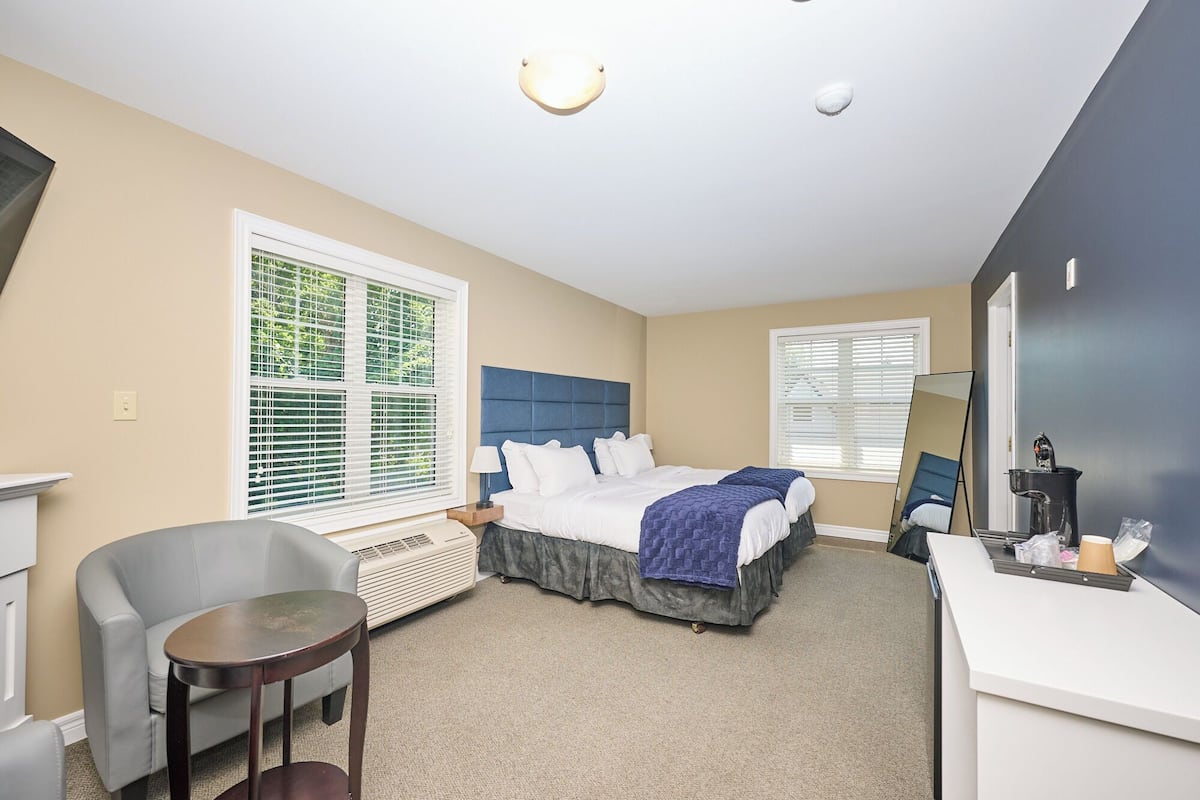 Een hotelkamer met een bed, een bureau, een stoel en een groot raam met zonwering.