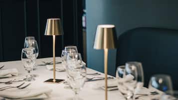 A dining table set with glasses, cutlery, and a lamp.