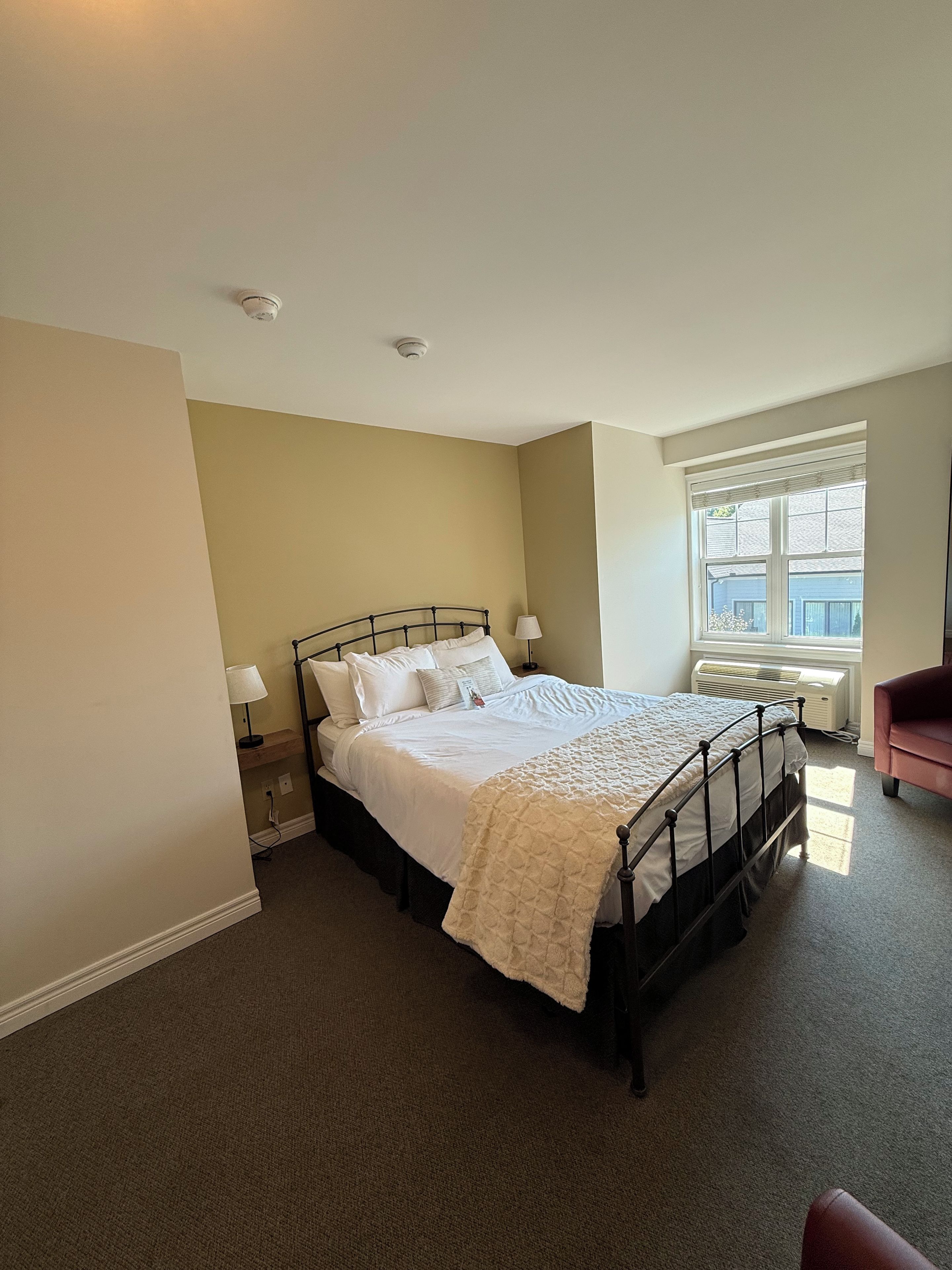 A bedroom with a bed, bedside lamps, a window, and a radiator.