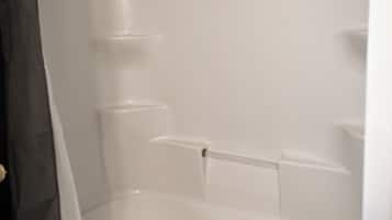 Una bañera con cortina de ducha, una toalla y un estante.