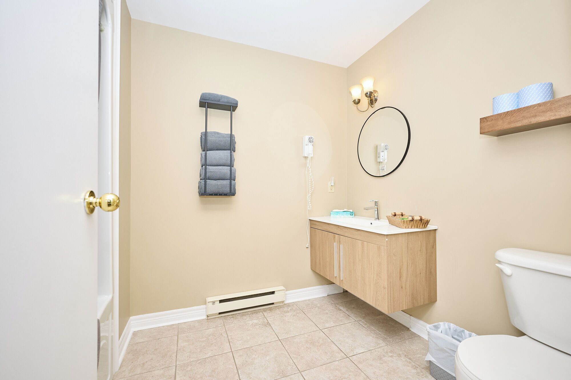 A bathroom with a toilet, sink, vanity, towel rack, and a wall-mounted mirror.