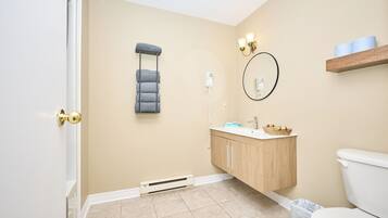 Ein Badezimmer mit Toilette, Waschbecken, Waschtisch, Handtuchhalter und einem Spiegel an der Wand.