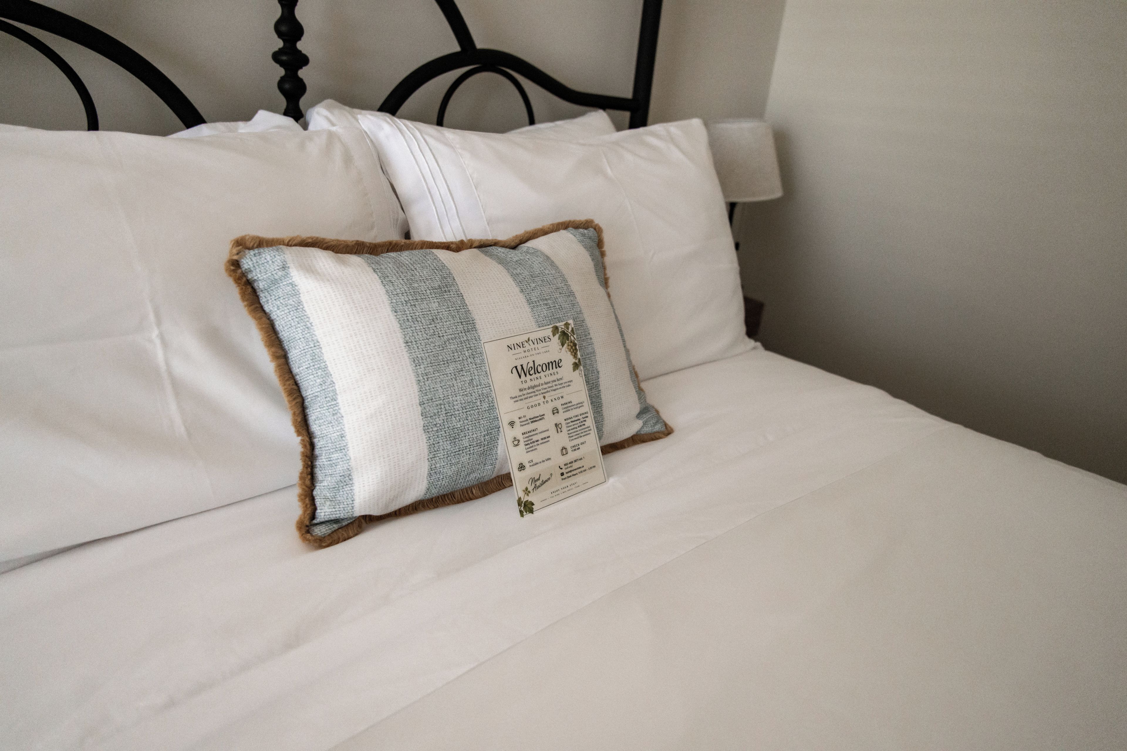 A bed with white linens and a single decorative pillow.