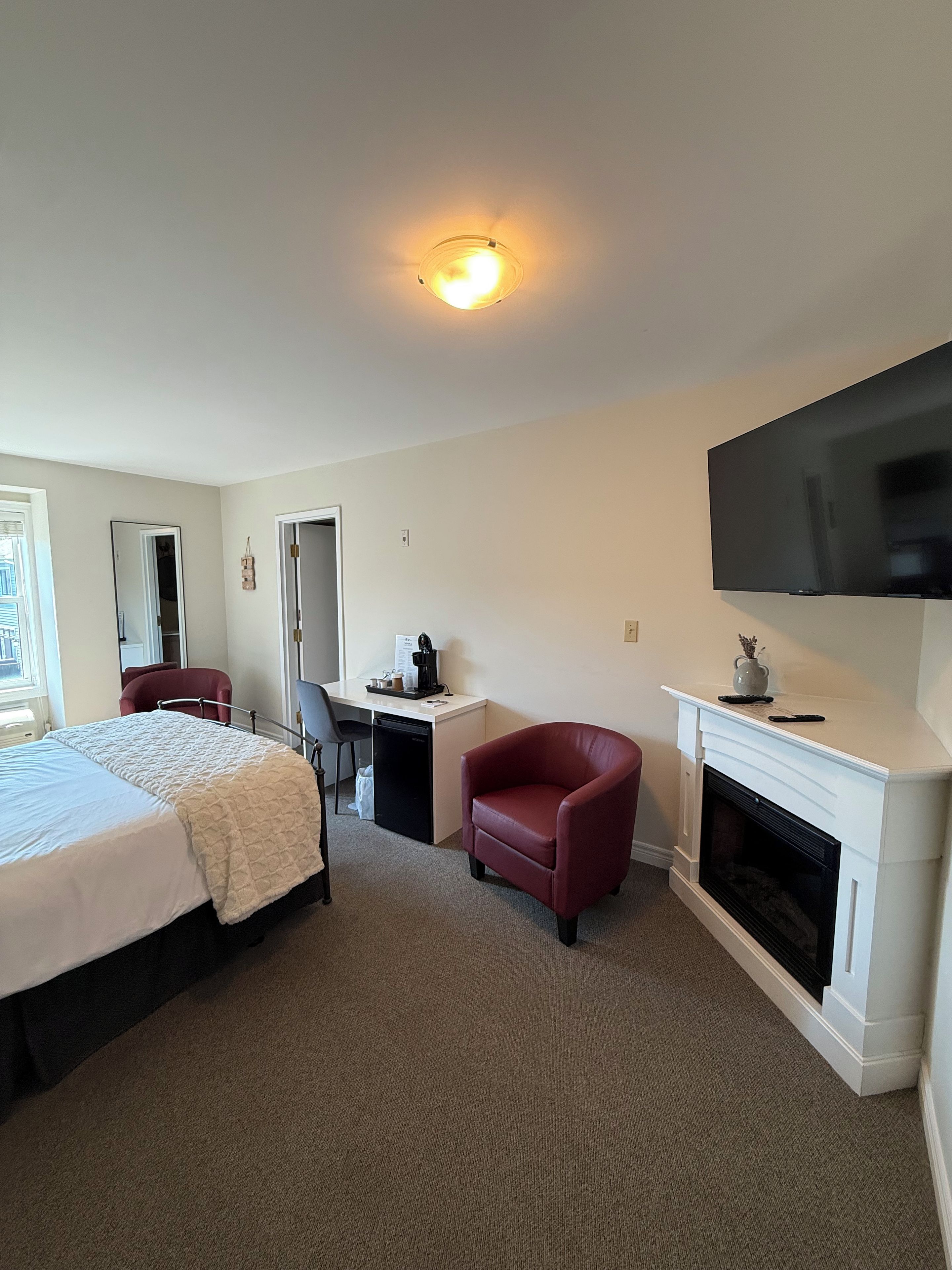 Habitación de hotel con cama, escritorio, silla, chimenea y televisor.